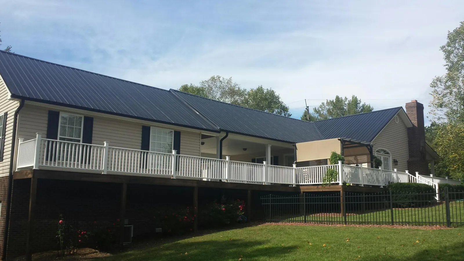 Black metal roof above a long white railed deck on a hillside home in Georgetown
